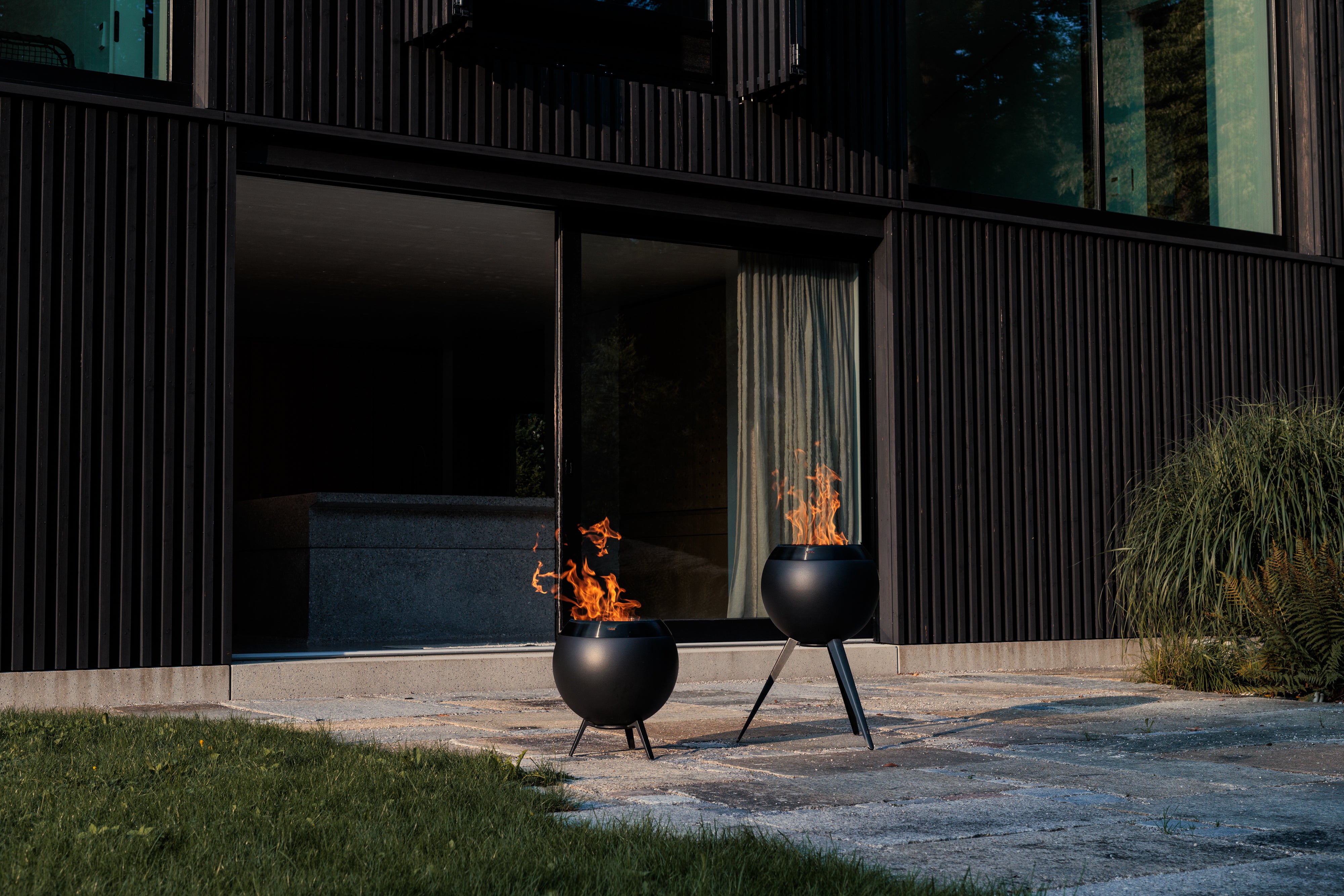 Höfats Moon 45 all Black Feuerkorb mit niedrigem und hohem Fuß auf der Terasse brennend